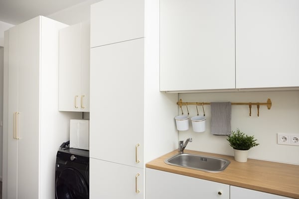 A kitchen and utility area with a built-in washing machine and cabinets visually integrated into the kitchen design.