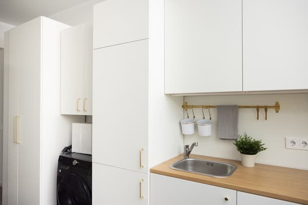 A kitchen and utility area with a built-in washing machine and cabinets visually integrated into the kitchen design.