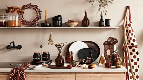 A kitchen countertop and shelf filled with the new KRÖSAMOS collection of glass jars, gift bags and serving trays.
