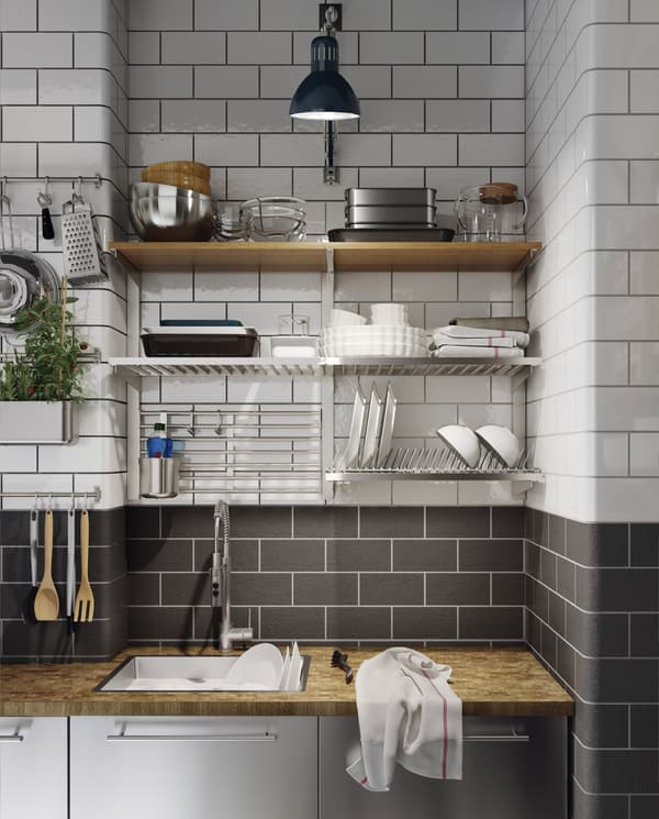 A kitchen in stainless steel with a wood worktop, a blue work lamp and a dish drainer, rails and shelves are wall-mounted.