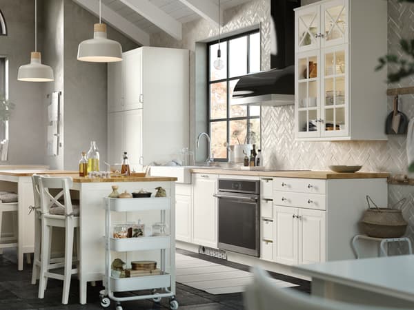 A kitchen in traditional style with BODBYN fronts in off-white, BUNKEFLO pendant lamps over a TORNVIKEN kitchen island.