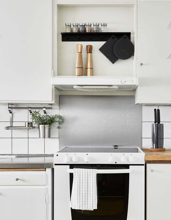 A kitchen is updated using easy, space-saving ideas. By adding a hanging rail for drying the dishes and to store extra utensils for cooking, you free up worktop space.