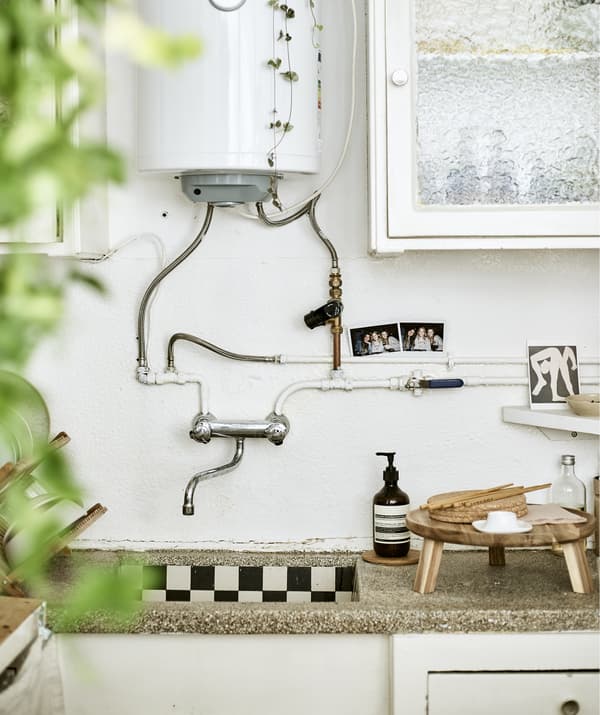 A kitchen sink with boiler unit, closed cupboards and wooden serveware.