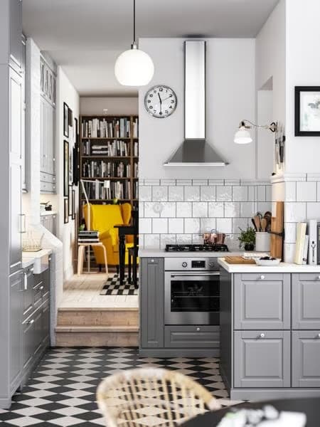 A kitchen with a chequered floor, grey BODBYN fronts with off-white/chrome plated handles and knobs, plus a pendant lamp.