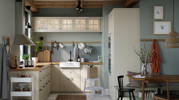 A kitchen with beige STENSUND drawer fronts and glass doors, oak effect worktops and a white sink bowl with visible front.