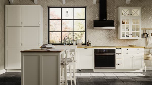 A kitchen with BODBYN doors and drawer fronts in off-white and a TORNVIKEN kitchen island with books on it.