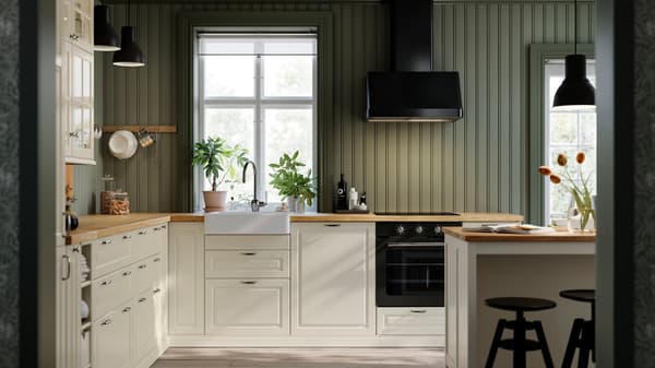A kitchen with BODBYN doors and drawer fronts in off-white, and a FOKUSERA wall-mounted extractor hood in black.
