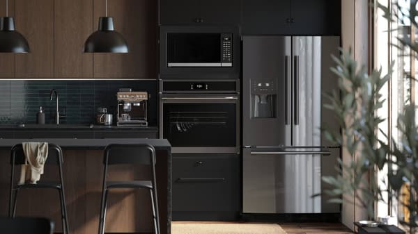 A kitchen with dark brown cabinet fronts and a fridge, oven and microwave showing
