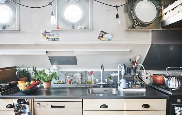 A kitchen with dark worktops and three porthole windows above.