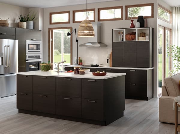 A kitchen with drawers and doors in dark brown ash effect and a kitchen island with a worktop in white/quartz.