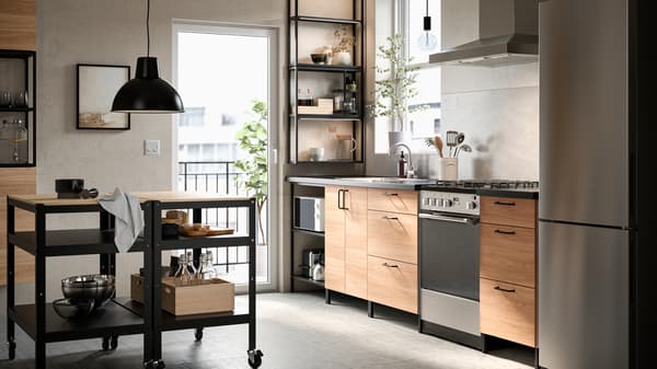 A kitchen with ENHET oak effect fronts, a VINSTGIVANDE wall-mounted extractor hood in stainless steel and BROR carts.