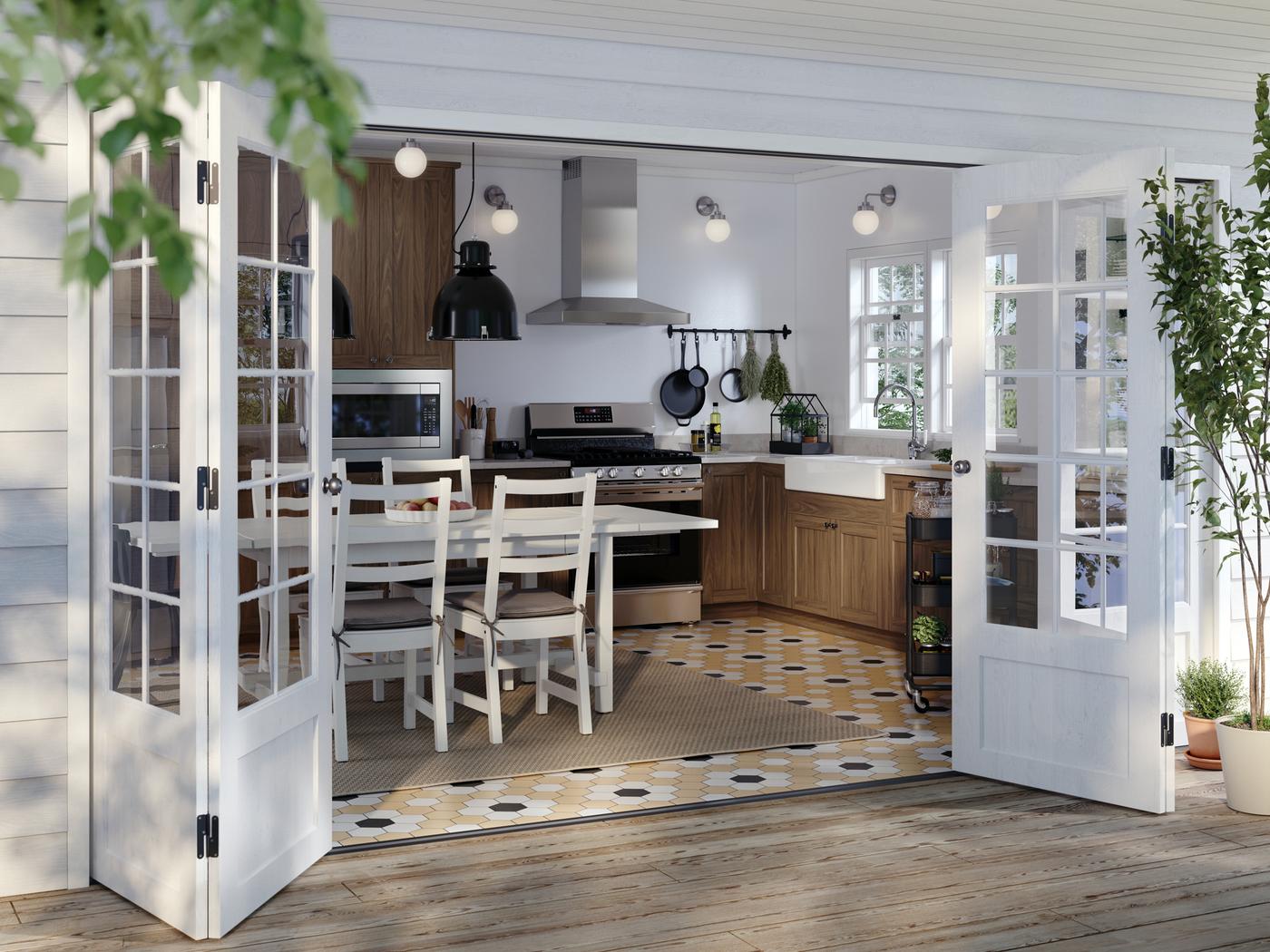 A kitchen with ENKÖPING kitchen fronts in brown, the doors to a deck are open, and a GRUNDLÄGGA range with gas cooktop.