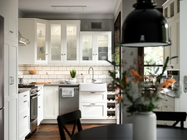 A kitchen with ENKÖPING white fronts, a CIRKULERA range in stainless steel, a HAVSEN sink bowl and a SVARTNORA pendant lamp.