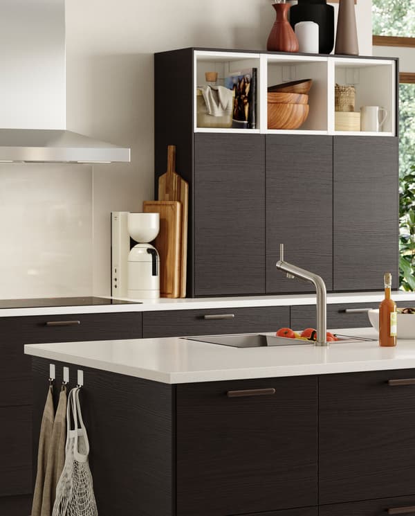 A kitchen with fronts in brown ash effect and a kitchen island with a kitchen mixer tap and an inset sink in stainless steel.