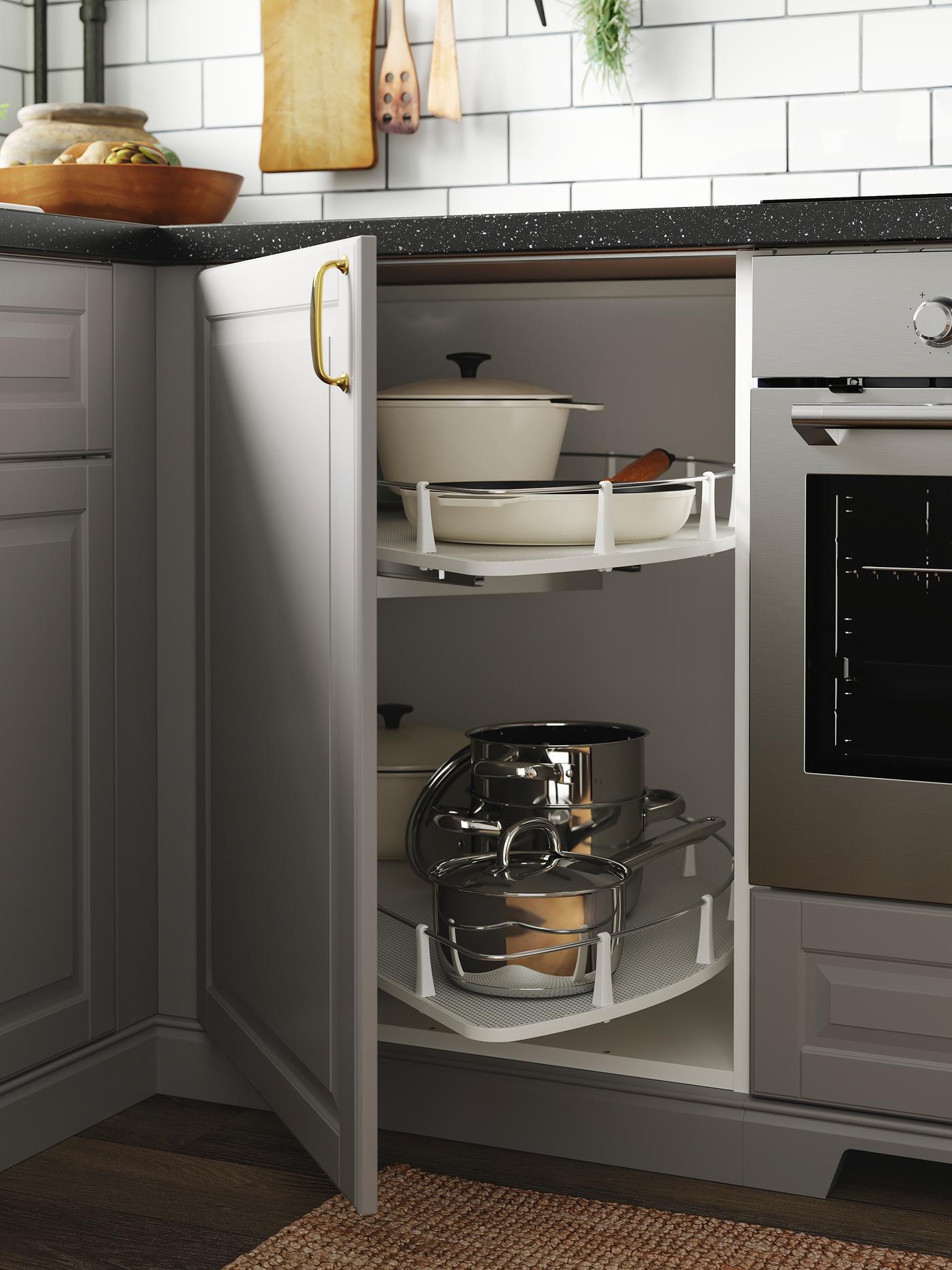 A kitchen with grey doors and an open corner cabinet where a carousel stores pots, pans and dishes.