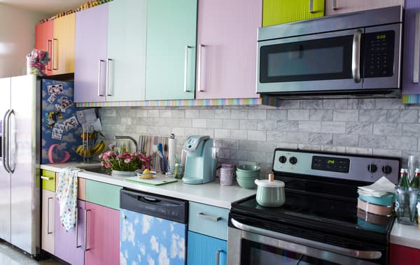 A kitchen with multicoloured doors and a white worktop.