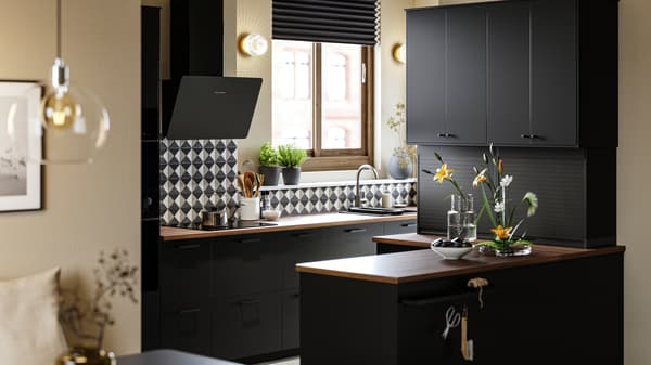 A kitchen with NICKEBO doors in anthracite, a FINSMAKARE wall mounted extractor hood in black and PERSILLADE plant pots.