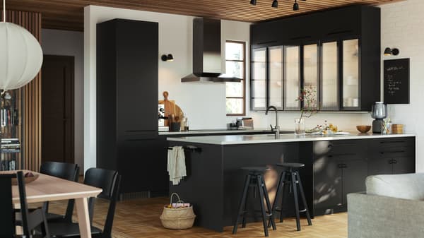 A kitchen with NICKEBO fronts, cabinets with HEJSTA glass doors in anthracite/reeded glass and DALFRED bar stools in black.