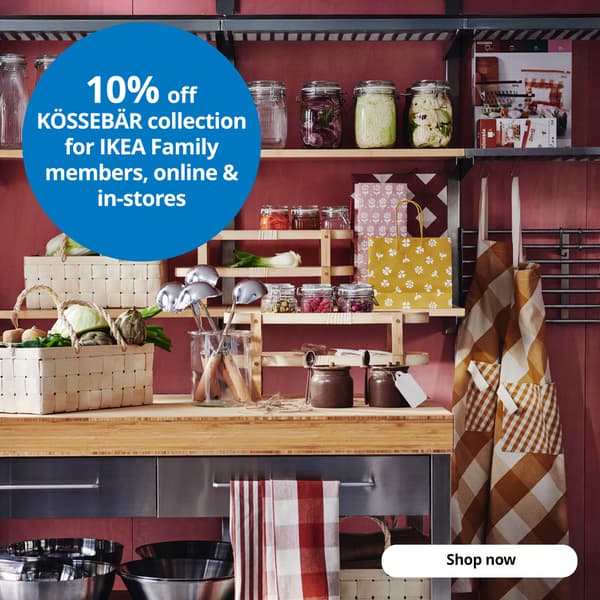 A kitchen with shelves and a table adorned with several KÖSSEBÄR items, like baskets, jars, tea towels, aprons, and more. A blue circle with white text that reads, 