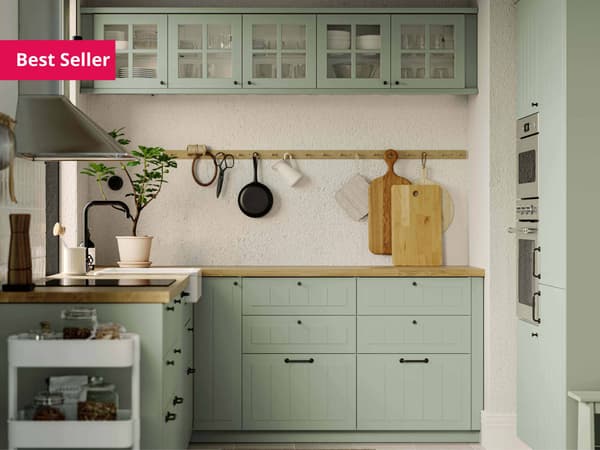 A kitchen with STENSUND sage green fronts, a GRUNDAD induction hob in black and a MATTRADITION wall-mounted extractor hood.