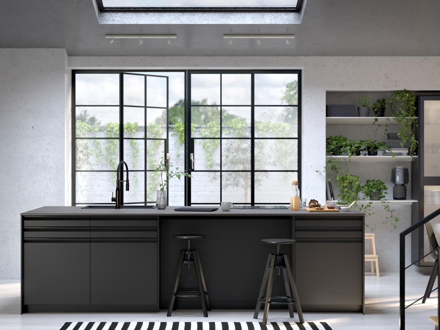 A kitchen with UPPLÖV anthracite fronts, DALFRED bar stools in black and FÖRDELAKTIG induction hob with integrated extractor.