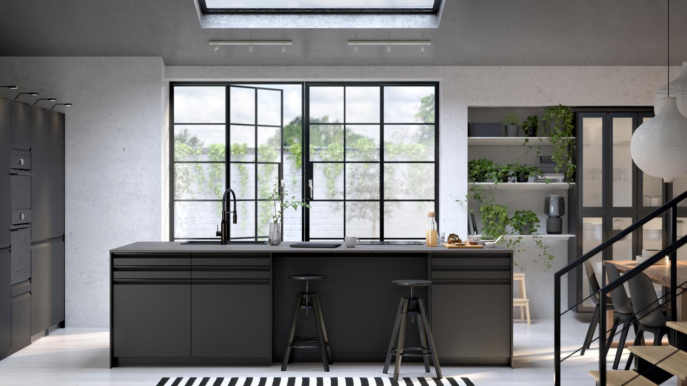 A kitchen with UPPLÖV anthracite fronts, DALFRED bar stools in black and FÖRDELAKTIG induction hob with integrated extractor.