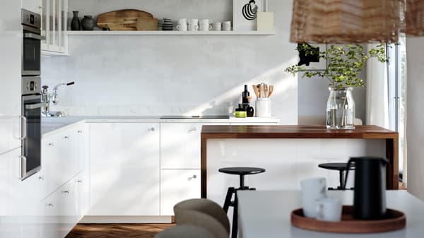 A kitchen with white high-gloss RINGHULT fronts and HEJSTA glass doors has a picture ledge on the wall and a kitchen island.