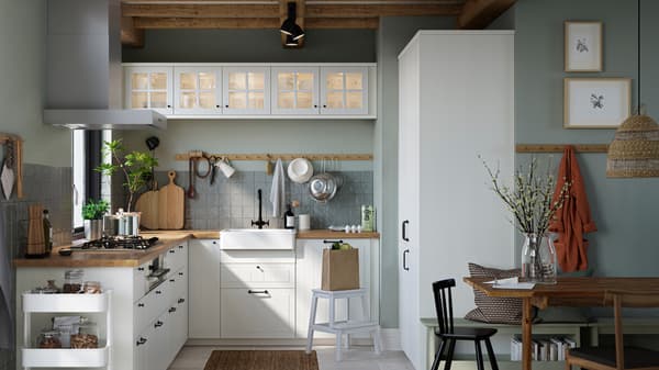 A kitchen with white STENSUND drawer fronts and glass doors, oak effect worktops and a white sink bowl with visible front.