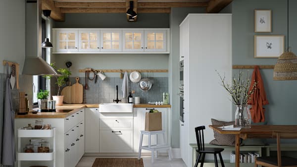 A kitchen with white STENSUND drawer fronts and glass doors, oak effect worktops and a white sink bowl with visible front.