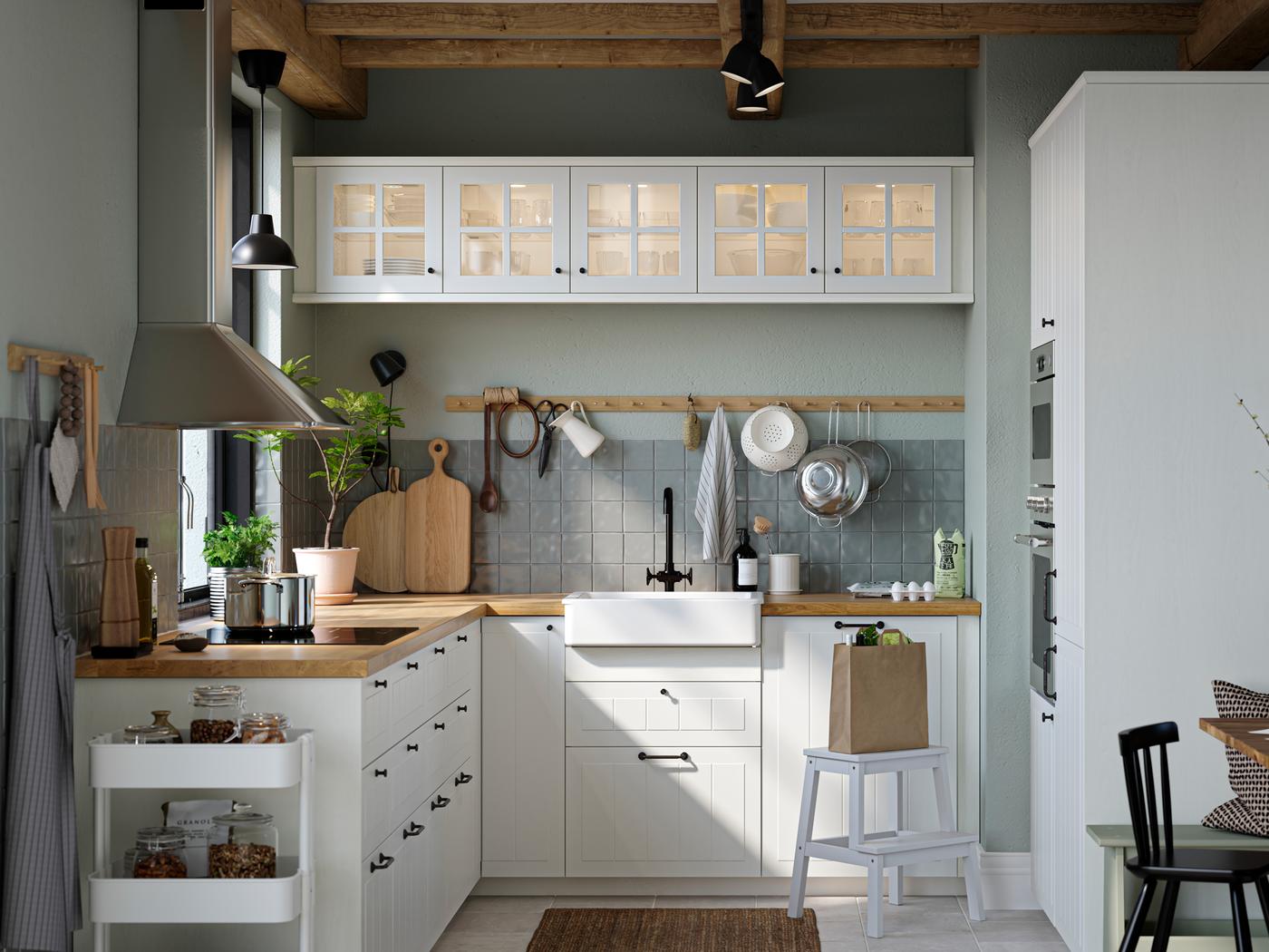 A kitchen with white STENSUND drawer fronts and glass doors, oak effect worktops and a white sink bowl with visible front.