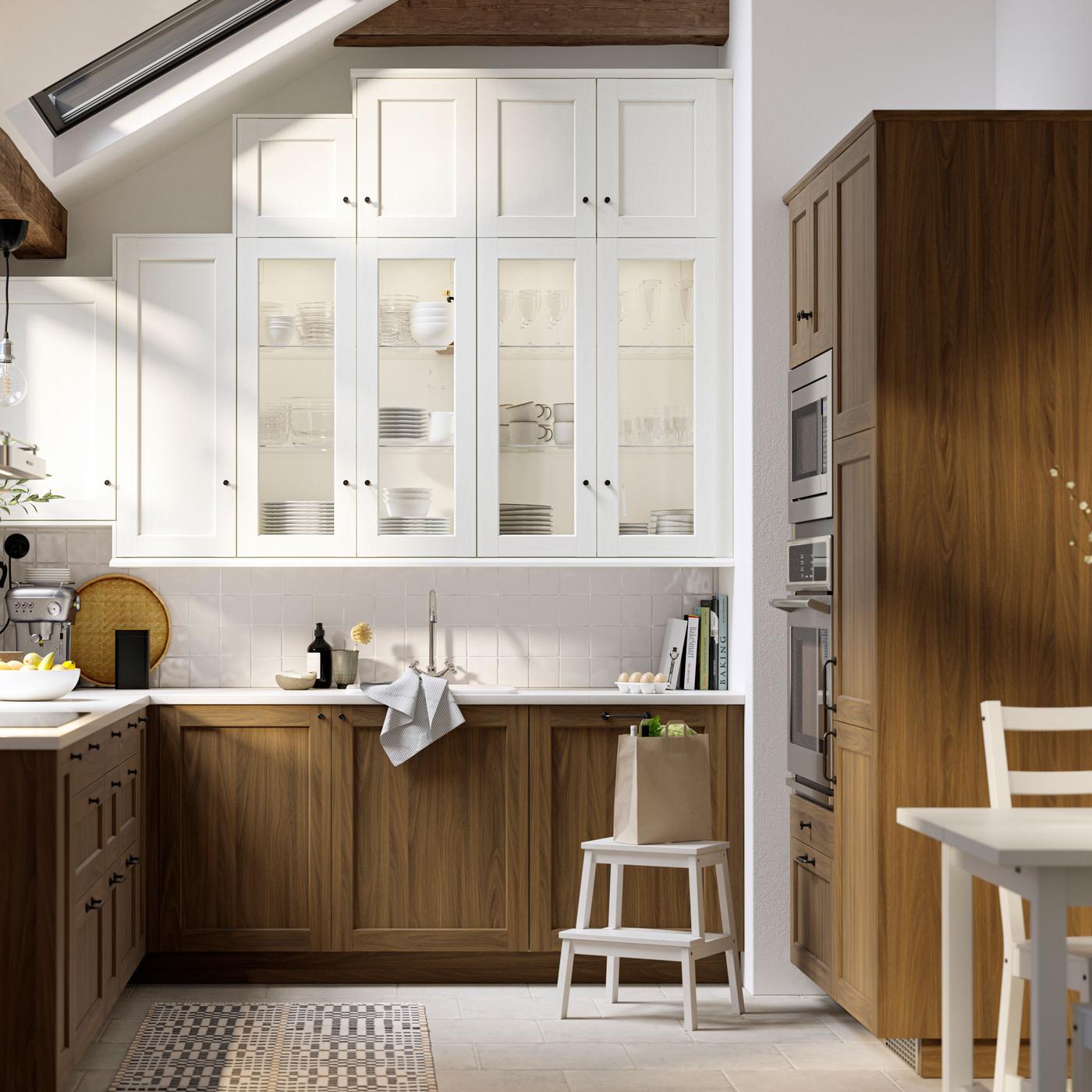A kitchen with white STENSUND drawer fronts and glass doors, oak effect worktops and a white sink bowl with visible front.