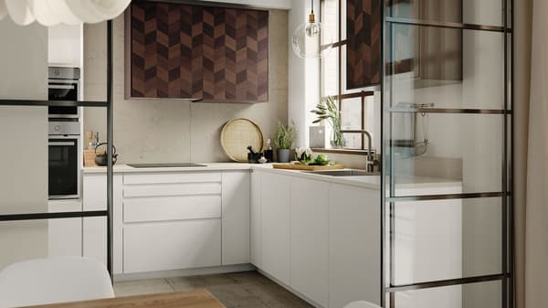A kitchen with white tiles and white VEDDINGE kitchen fronts, kitchen utensils hang from hooks on a wall-mounted rail.