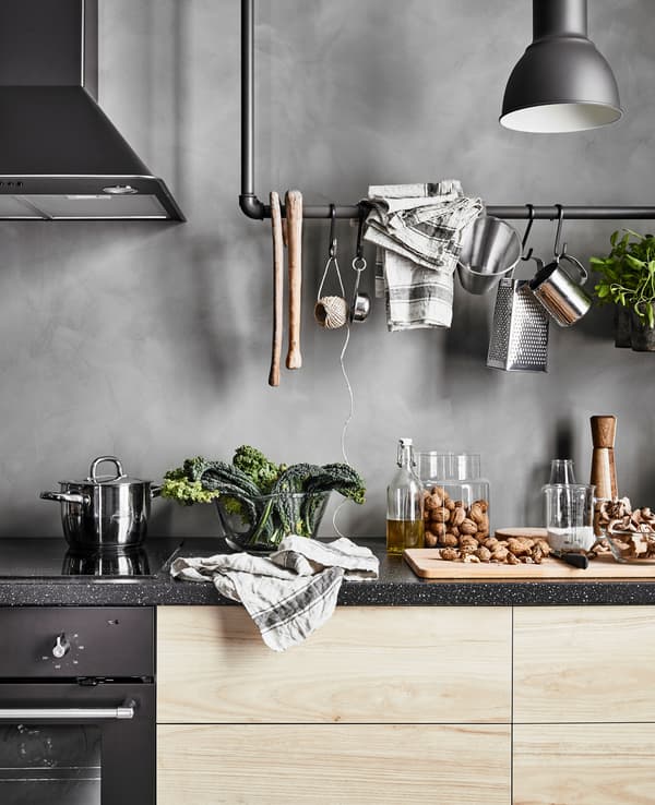 A kitchen worktop with a granite effect on ash effect drawers next to a hob, oven and hood vent 