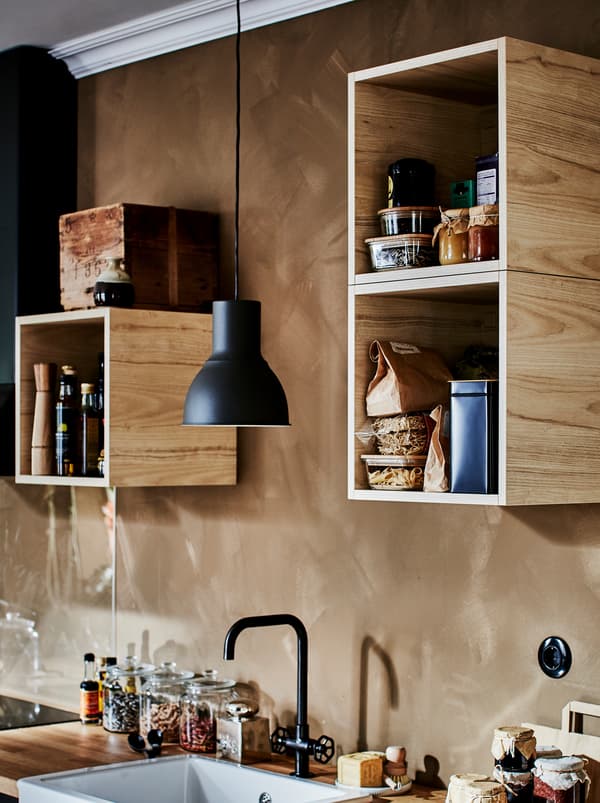 A különféle konyhai kiegészítőkkel megtöltött TUTEMO szekrények rendszertelenül elhelyezve a falon, a konyhasarok felett.