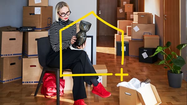 A lady is packing up a vase in a room full of moving boxes