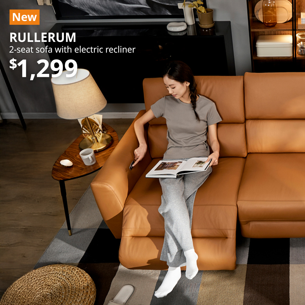 A lady sitting on a grann/bomstad golden-brown RULLERUM 2-seat sofa with electric recliner, adjusting the recliner to her comfort in a living room setting. An orange "NEW" label is on the top left of the image with black text that reads: RULLERUM, 2-seat sofa with electric recliner, $1,299.