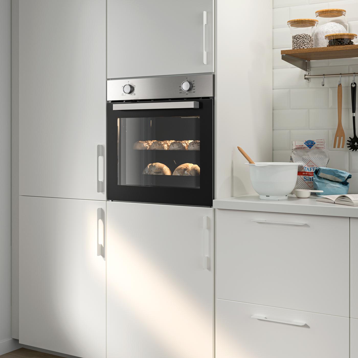 A LAGAN stainless steel oven integrated within a white kitchen with white handles and a white worktop