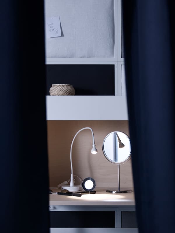 A lamp and mirror sit inside a bureau to provide a place to groom without turning on other bright bedroom lights.