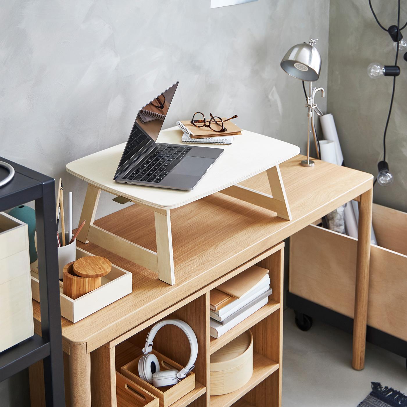 A laptop, notepads and spectacles on a birch plywood, RÅVAROR tray that stands on an oak veneer, RÅVAROR console table.