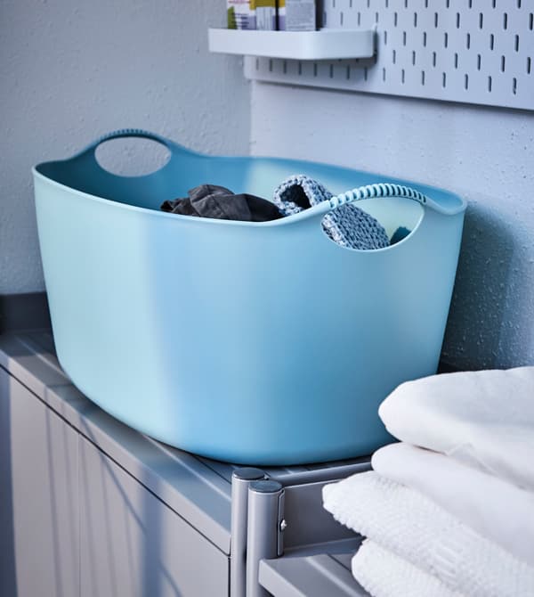 A large blue laundry basket sits on top of a cabinet.