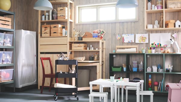 A large IVAR storage combination in natural pine and dark green, filled with boxes, hobby accessories and kid’s art stuff.