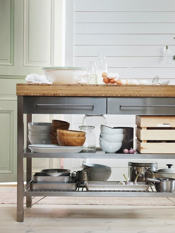 A large kitchen island is used for baking on top and holds lots of kitchenware on the shelves below.