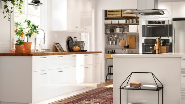 A large open kitchen with an island that combines white RINGHULT doors in high gloss with an oak countertop.