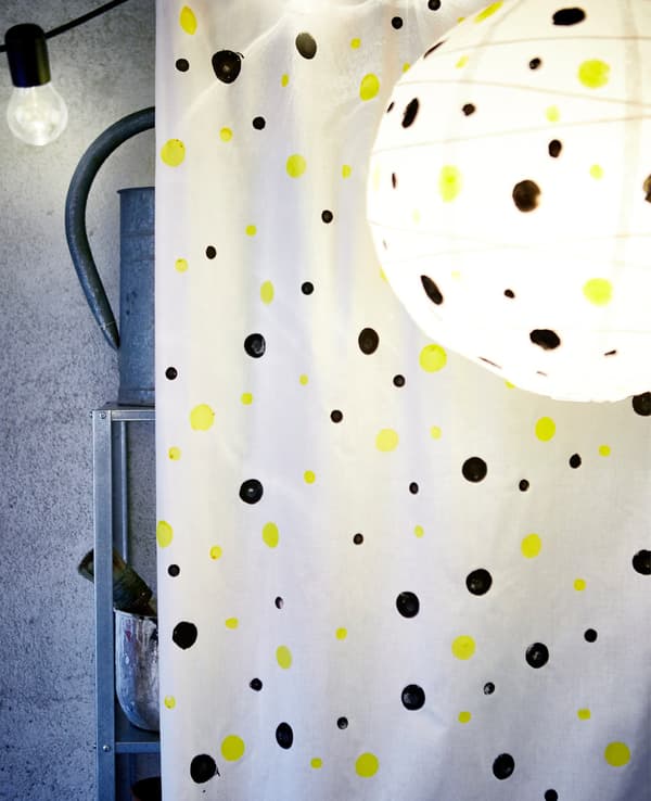A large piece of fabric covered in painted dots used to cover up metal shelving in a garage.