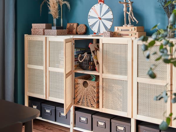 A lattice-front wall storage unit with one door open and storage boxes inside, plus storage boxes and accessories on top.