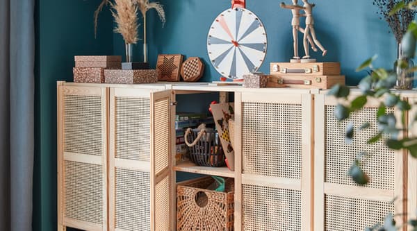 A lattice-fronted wall storage unit with one door open and storage boxes inside, plus storage boxes and accessories on top.