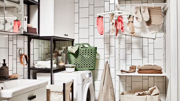 A laundry area with shelves and cabinets, a SLIBB hang dryer and a green SLIBB flexible laundry basket.