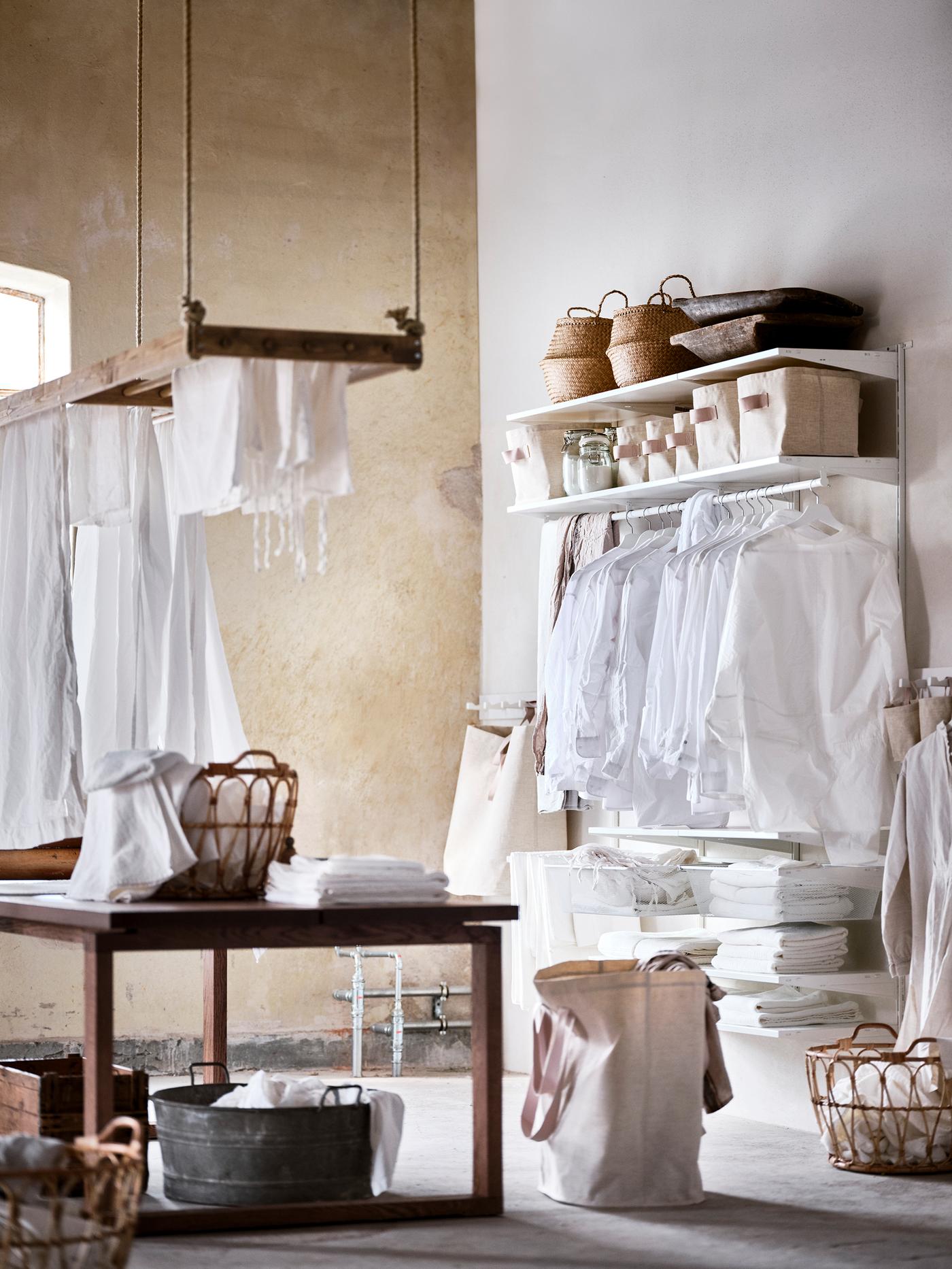  A laundry room with a brown wooden table in the center and a BOAXEL system mounted on the white wall.