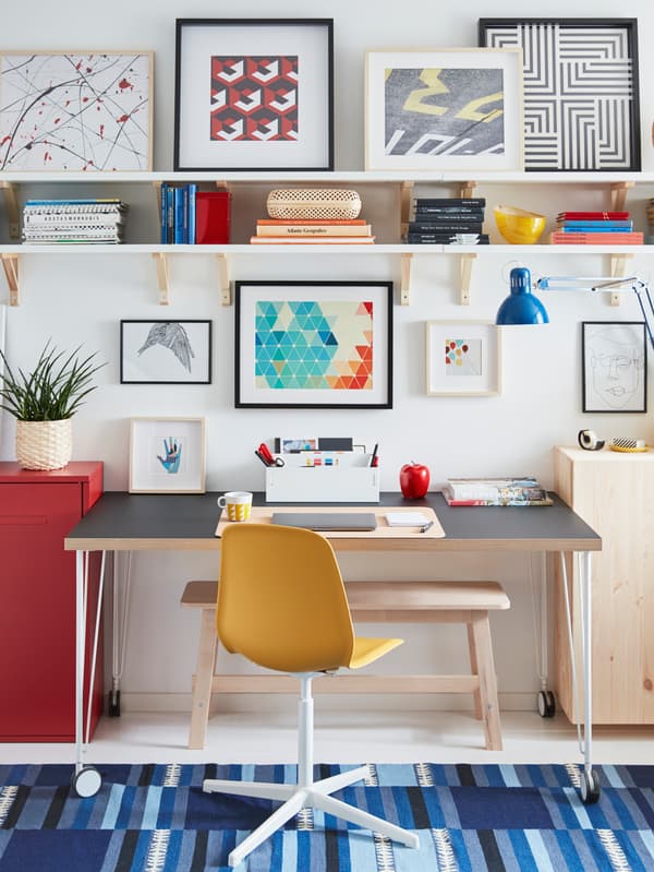 A LEIFARNE swivel chair and a LINNMON/KRILLE wheeled desk form a workspace by a wall, surrounded by storage and art.