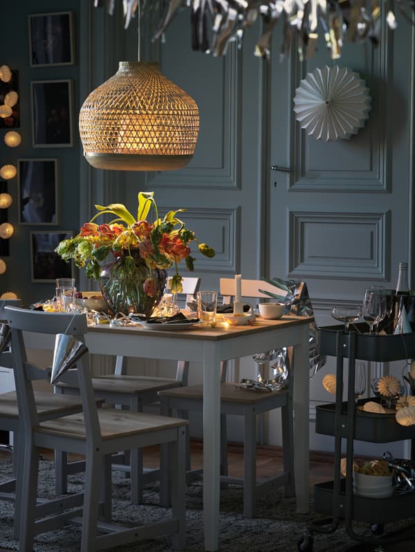 A LERHAMN table is decorated with dinnerware and flowers for a festive meal, with a RÅSKOG trolley at its side.